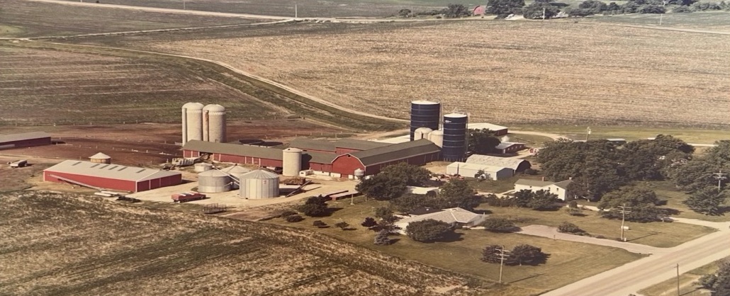 Fotografía aérea antigua del sitio original de Hickory Hill Farms — establos rojos, silos y campos en Wisconsin